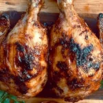 Golden Brown Charcoal Chicken With Crispy Skin, Served On A Rustic Wooden Board With Fresh Herbs