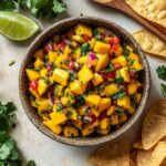 Fresh mango salsa in rustic bowl with lime and cilantro