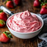 Strawberry cream cheese frosting in a bowl with fresh strawberries