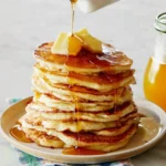 Stack of fluffy pancakes with syrup and berries on a plate