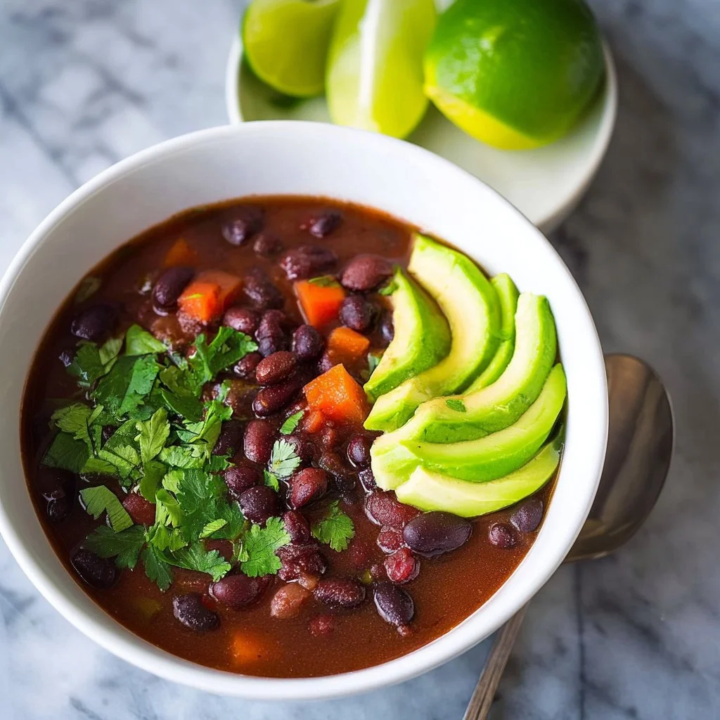 Bowl of rich black bean soup garnished with cilantro and lime