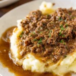 Plate of ground beef and gravy served with mashed potatoes and vegetables