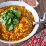 Bowl of vegan red lentil curry with rice and vegetables