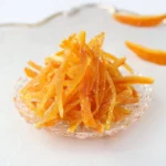 Homemade candied orange peel on a wooden surface.