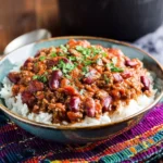Delicious bowl of classic chili with meat, topped with cheese and herbs