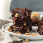 Plate of classic fudge walnut brownies topped with walnuts