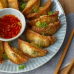Plate of crispy deep-fried dumplings served with dipping sauce