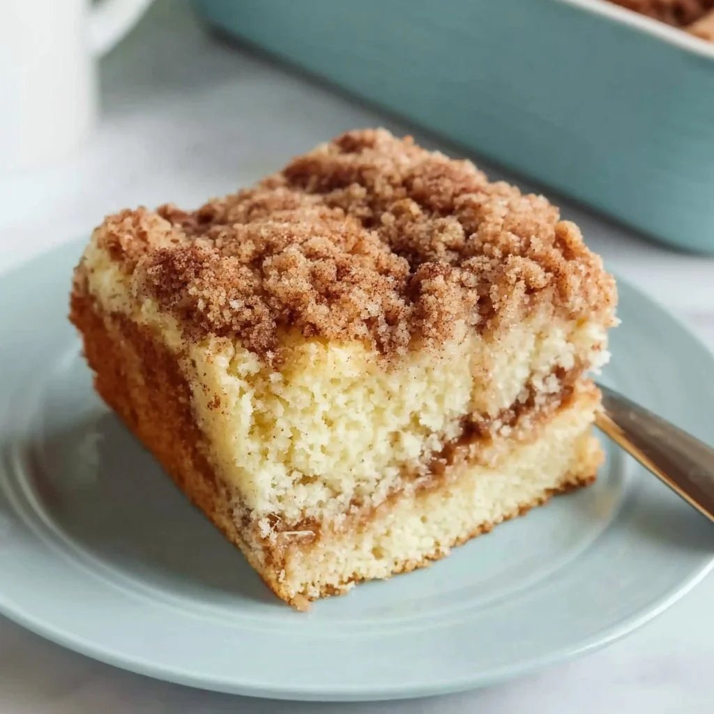 Delicious sour cream coffee cake served on a plate with a coffee cup