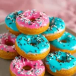 Freshly baked donuts topped with icing and sprinkles on a plate