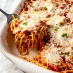 Delicious baked spaghetti served with cream cheese, garnished with herbs