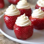 Cheesecake-stuffed strawberries on a plate, topped with whipped cream