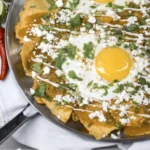 Chilaquiles topped with cheese and avocado, a comforting dish for busy days.