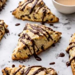 Freshly baked chocolate chip scones on a rustic wooden table.