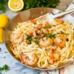 Creamy shrimp linguine served in a bowl, garnished with parsley and lemon.