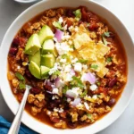 Bowl of delicious ground chicken chili garnished with herbs