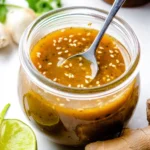 Asian Sesame Ginger Dressing in a glass jar with fresh ingredients.