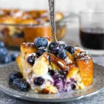 Baked blueberry French toast casserole topped with fresh blueberries and syrup
