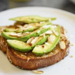 Delicious Coconut Avocado Toast topped with fresh coconut and garnished with herbs
