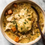 Bowl of creamy chicken stew with dumplings garnished with parsley