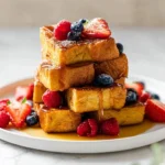 Delicious plate of homemade French Toast Sticks served with syrup.