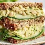 High protein avocado white bean sandwich with fresh ingredients on a plate.
