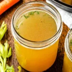 Homemade Instant Pot chicken broth in a bowl, garnished with herbs.