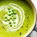 Bowl of delicious green pea soup garnished with fresh herbs