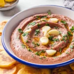Delicious red kidney bean hummus topped with roasted garlic served in a bowl