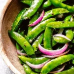 A bowl of roasted sugar snap peas seasoned and ready to enjoy.