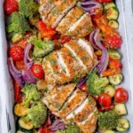 Sheet pan baked chicken breast with colorful veggies ready to serve