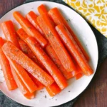 Bowl of simple steamed carrots garnished with herbs.