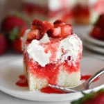 Slice of strawberry poke cake topped with fresh strawberries and whipped cream