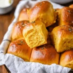 Freshly baked sweet potato dinner rolls on a wooden table