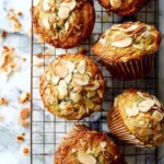 Freshly baked Almond Lemon Poppy Seed Muffins on a wooden table.