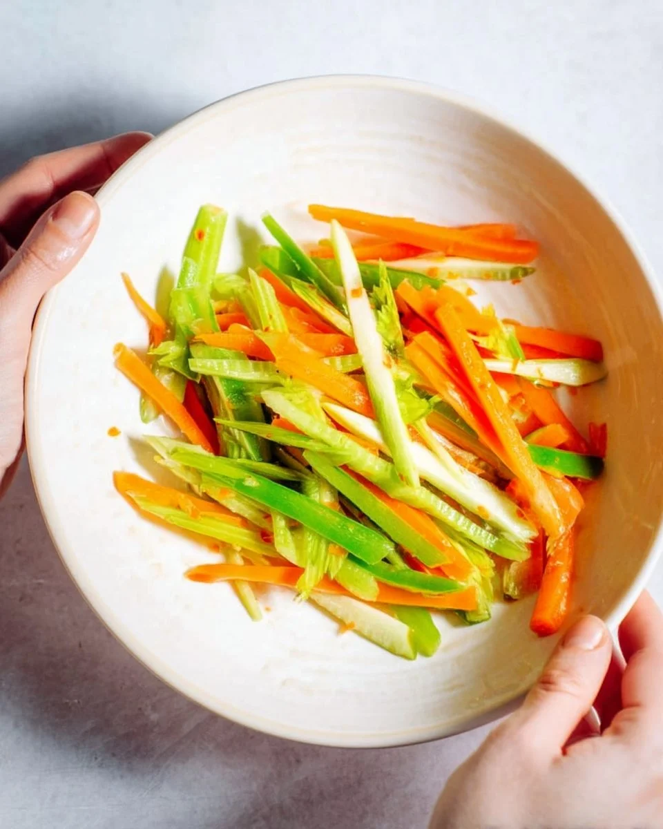 Colorful Asian carrot celery slaw served in a bowl, garnished with sesame seeds.