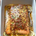 Delicious baked honey mustard salmon on a plate with herbs and lemon