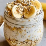 A bowl of creamy banana cream pie overnight oats topped with banana slices.