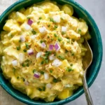 Creamy egg salad in a bowl, garnished with fresh herbs and served with bread.