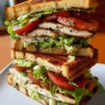 Garlic butter lettuce tomato and grilled chicken sandwich served on a plate.