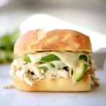 Pulled chicken sandwich with creamy ranch sauce on a wooden board