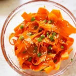 Fresh raw carrot salad with herbs and dressing in a bowl