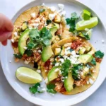 Shredded chicken and zucchini tacos served on a plate with fresh toppings.