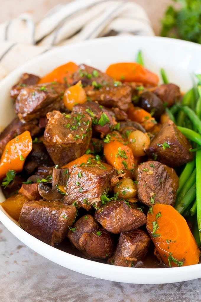 A bowl of slow cooker beef bourguignon garnished with herbs