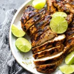 Grilled tequila lime chicken garnished with fresh lime and herbs