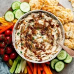 Creamy caramelized onion dip served with fresh vegetables and chips