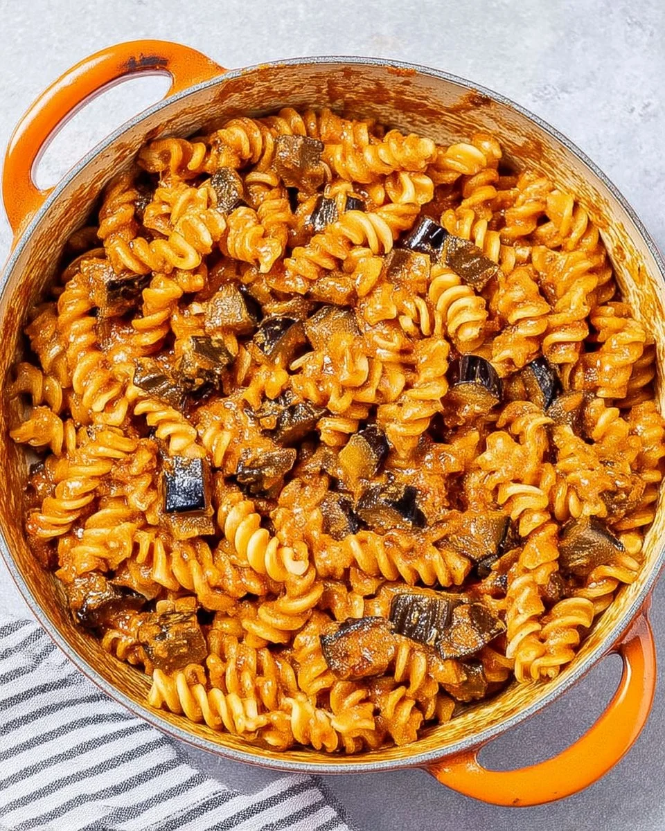 Creamy eggplant pasta dish served in a bowl with fresh herbs and cheese
