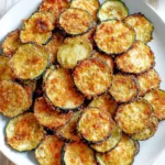 Baked zucchini chips displayed on a serving plate, crispy and healthy snack