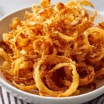 A plate of crispy onion strings, golden and crunchy, served as a snack or topping.