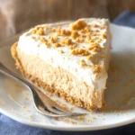 Slice of easy peanut butter pie on a plate with whipped cream garnish