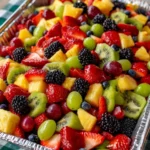 A large bowl of vibrant fruit salad made for a crowd at a summer gathering